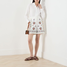 Model wearing Max Mara Weekend Obice Embroidered Shorts in White Cross with floral embroidery, styled with a white blouse and brown sandals.