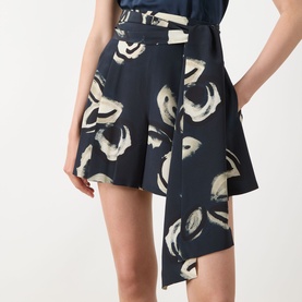Model wearing navy abstract floral print wide-leg shorts with draped front detail, styled with matching navy top