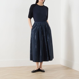 Model wearing Max Mara Weekend Fiordi Embellished Flared Skirt in navy, midi length with metallic detailing, styled with a black top and flat shoes.