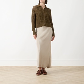 Model wearing Max Mara Main stone silk maxi skirt, styled with olive crochet cardigan and brown strappy sandals.