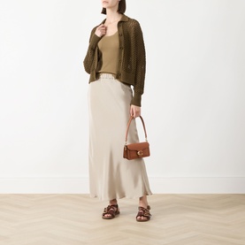 Model wearing Max Mara Main stone silk midi skirt, styled with olive knit cardigan, tan top, brown sandals and tan shoulder bag.