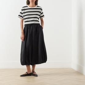 Model wearing Max Mara Weekend Ciurma Bubble Skirt in black with elasticated waist and bubble hem, styled with a striped tee and black flat shoes.