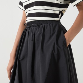 Model wearing Max Mara Weekend Ciurma Bubble Skirt in black with elasticated drawstring waist and side pockets, styled with a striped top.