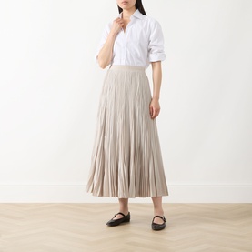 Model wearing Max Mara Weekend ivory pleated midi skirt, styled with a white shirt and black flat shoes.