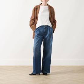Model wearing Max Mara Weekend Multia Logo Top in white, styled with wide-leg blue jeans, a tan jacket, and black flat shoes.