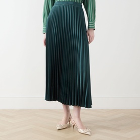 Model wearing Max Mara Weekend Nicchia Pleated Skirt in dark green, midi length with wide waistband. Styled with matching green top and gold heels.