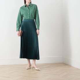 Model wearing Max Mara Weekend Nicchia Pleated Skirt in dark green, midi length with wide waistband, styled with a green striped shirt and nude mules.