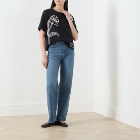 Model wearing Max Mara Weekend Sala Flower Boxy T-Shirt in black with white floral embroidery, styled with blue wide-leg jeans and black flats.