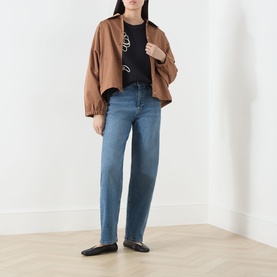 Model wearing Max Mara Weekend Sala Flower Boxy T-Shirt in Black Flowers, styled with tan jacket, blue straight-leg jeans and black ballet flats.