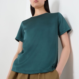 Model wearing Max Mara Weekend Gilvert Fluid Blouse in green, featuring round neckline, short sleeves and straight hemline, styled with tan trousers.