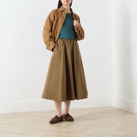 Model wearing Max Mara Weekend Gilvert Fluid Blouse in green, styled with a camel gathered midi skirt, jacket, and brown loafers.