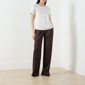 Model wearing Max Mara Weekend Gilbert Solid Blouse in ivory with crew neckline and short sleeves, styled with dark brown wide-leg trousers.