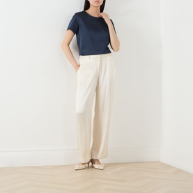 Model wearing Max Mara Weekend Gilbert Solid Blouse in navy, crew neck, satin finish, short sleeves, styled with cream wide-leg trousers and nude