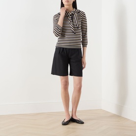 Model wearing Max Mara Main stone striped knit top with bow neck detail, styled with black shorts and black ballet flats