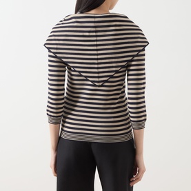 Model wearing Max Mara Main stone and black stripe top, rear view, showing ruffle shoulder detail and three-quarter sleeves, with black trousers.