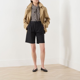 Model wearing Max Mara Main stone striped top with black tailored shorts, camel cropped jacket, and black ballet flats.