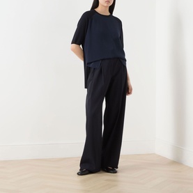 Model wearing Max Mara Golfo Two-Tone Knitted Sweater in Ultramarine with crew neck, high-low hem, styled with wide-leg black trousers.