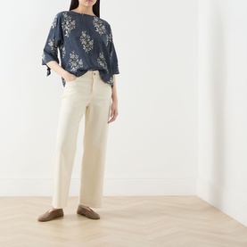 Model wearing navy floral print oversized top with tie sleeves, styled with cream wide-leg trousers and tan flat shoes