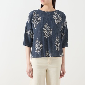 Model wearing navy blue floral print cropped top with three-quarter sleeves, styled with cream wide-leg trousers