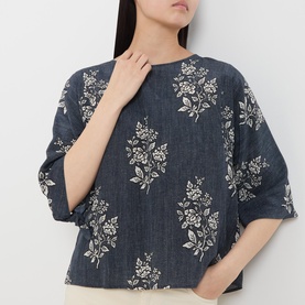 Model wearing navy blue floral print cropped top with elbow-length sleeves and crew neckline, featuring cream botanical embroidery pattern