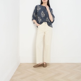 Model wearing navy floral print oversized top with wide-sleeve silhouette, styled with cream wide-leg trousers and tan flat shoes