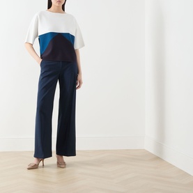 Model wearing Max Mara Main navy colour-block top with white, teal and burgundy panels, styled with wide-leg navy trousers and nude heels.