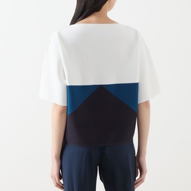 Model wearing Max Mara Main navy colour-block top, white and teal geometric back panel design, short sleeves, styled with navy trousers.