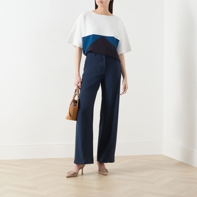 Model wearing Max Mara Main navy colour-block top with white and teal panels, styled with wide-leg navy trousers and nude heels.