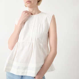 Model wearing Max Mara Weekend Vallo Peplum Blouse in white, with round neckline, sleeveless design, peplum hem and pleated details, styled with blue
