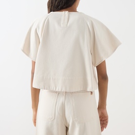 Model wearing Max Mara Weekend ecru cotton top, rear view, boxy fit with wide sleeves and elasticated hem, styled with matching trousers.