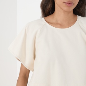 Model wearing Max Mara Weekend ecru cotton top with flutter raglan sleeves and round neckline, close-up detail view