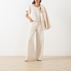 Model wearing Max Mara Weekend ecru cotton top with frill sleeves, styled with matching wide-leg trousers and an oversized jacket.