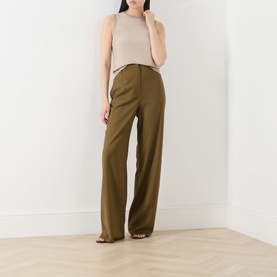 Model wearing Max Mara Main Ginseng Knitted Vest in Stone, crew neck, sleeveless, styled with wide-leg olive trousers and tan sandals