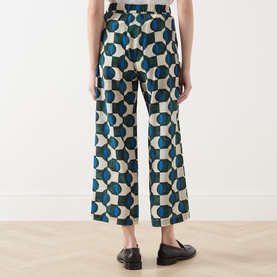Model wearing Max Mara Weekend Eusebio Silk Printed Trousers in dark green geometric print, cropped wide-leg cut, paired with black loafers