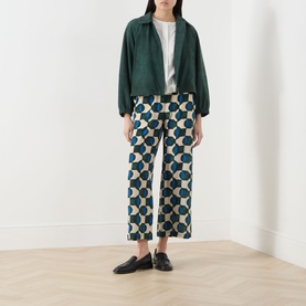 Model wearing Max Mara Weekend Eusebio Silk Printed Trousers in dark green geometric print, styled with green jacket and black loafers
