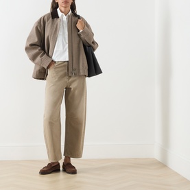 Model wearing Max Mara Weekend Arcadia Barrel-Leg Jeans in Beige Light, styled with a brown bomber jacket, white shirt and loafers