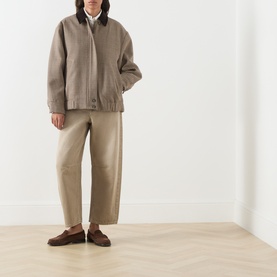 Model wearing Max Mara Weekend Arcadia Barrel-Leg Jeans in Beige Light, styled with a taupe bomber jacket, white shirt and brown loafers.