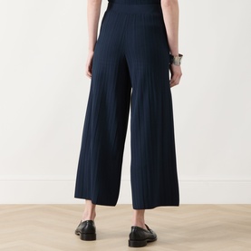 Model wearing Max Mara Weekend navy wide-leg ribbed trousers, styled with black loafers, rear view.
