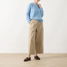 Model wearing Max Mara Weekend Libero Flared Trousers in beige, elasticated waist, wide-leg cut, styled with blue knit and brown loafers