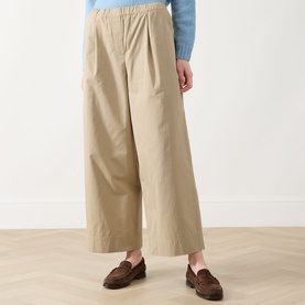 Model wearing Max Mara Weekend Libero Flared Trousers in beige, wide-leg cotton cut with elasticated waist, styled with blue top and brown loafers