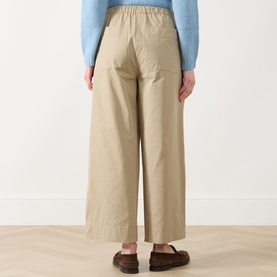 Model wearing Max Mara Weekend Libero Flared Trousers in beige, showing rear patch pockets and wide-leg cut, styled with a blue knit and brown
