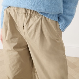 Model wearing Max Mara Weekend Libero Flared Trousers in beige with elasticated waistband, styled with a blue knit jumper.