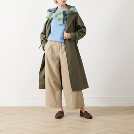 Model wearing Max Mara Weekend Libero Flared Trousers in beige with elasticated waist, styled with olive trench coat and blue sweater.