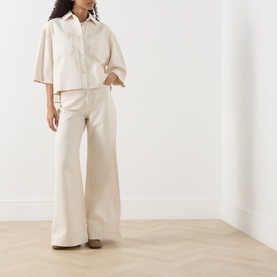 Model wearing Max Mara Weekend ecru wide-leg cotton trousers, styled with a matching ecru oversized shirt and brown loafers.
