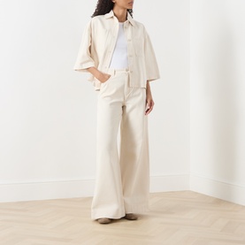 Model wearing Max Mara Weekend Ecru wide-leg cotton trousers, styled with a matching ecru oversized shirt and brown loafers.