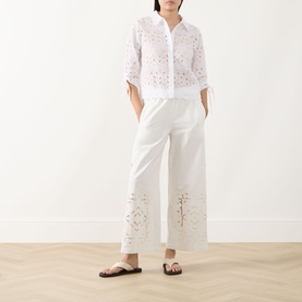 Model wearing Max Mara Weekend Guiliva Lace Cut-Out Wide-Leg Trousers in white with matching lace shirt and brown sandals.