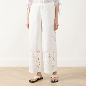 Model wearing Max Mara Weekend Guiliva Lace Cut-Out Wide-Leg Trousers in white with floral broderie detailing, styled with a white top and sandals.