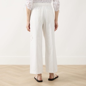 Model wearing Max Mara Weekend Guiliva Lace Cut-Out Wide-Leg Trousers in white, showing rear patch pockets and lace detailing, styled with black