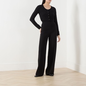 Model wearing black wide-leg trousers with a black long-sleeve button-front cardigan top and black flat shoes.