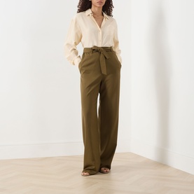 Model wearing Max Mara Main Editto Wide-Leg Trousers in kaki, high-rise with self-tie belt, styled with cream shirt and tan heeled sandals